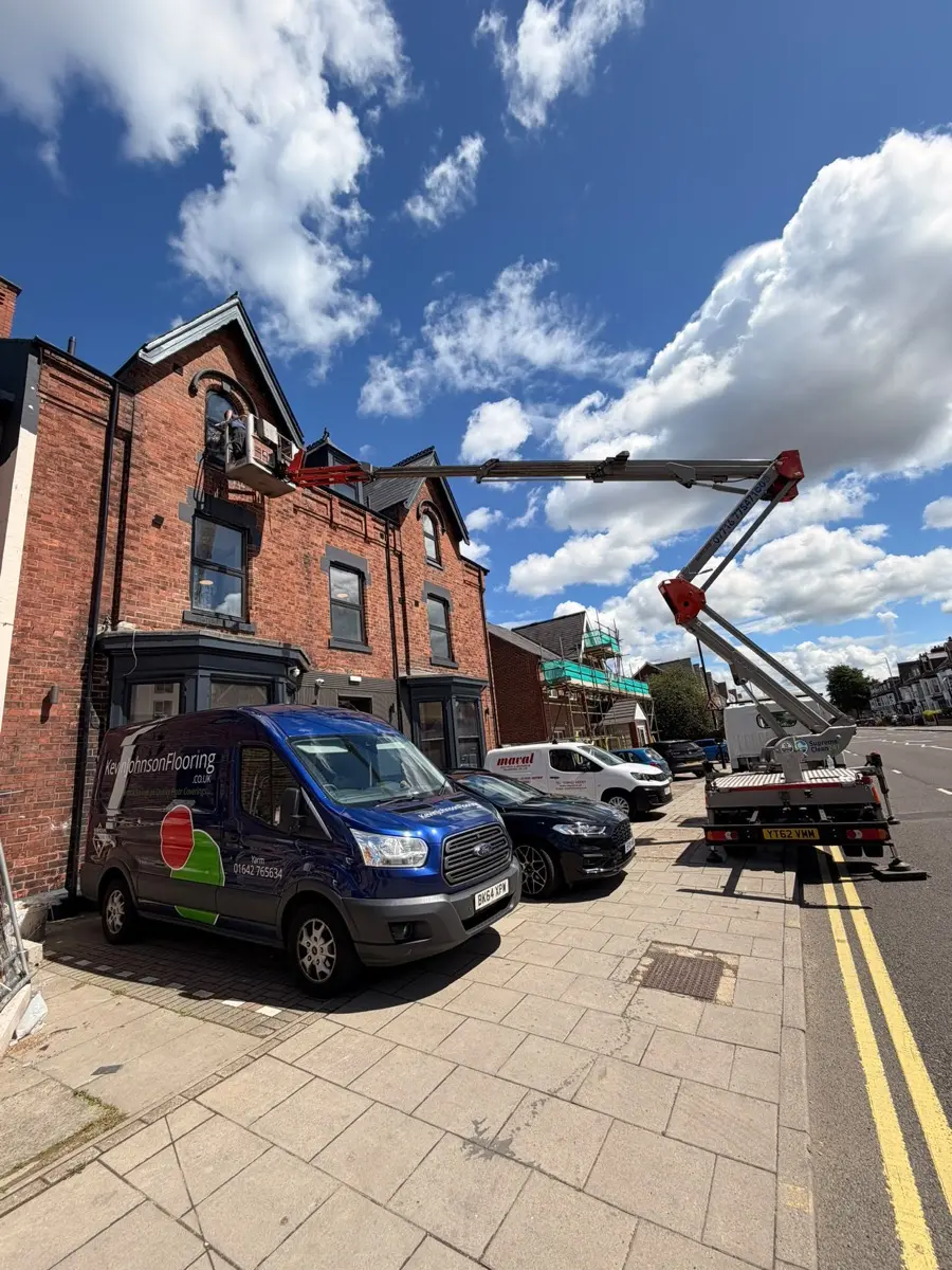 Cherry picker boom extended over a terraced building for high-level cleaning