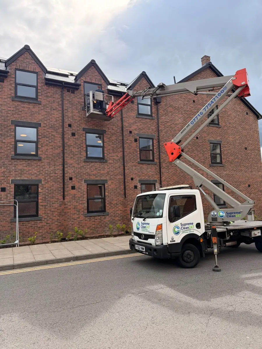 Van-mounted cherry picker reaching third-floor windows of an apartment block