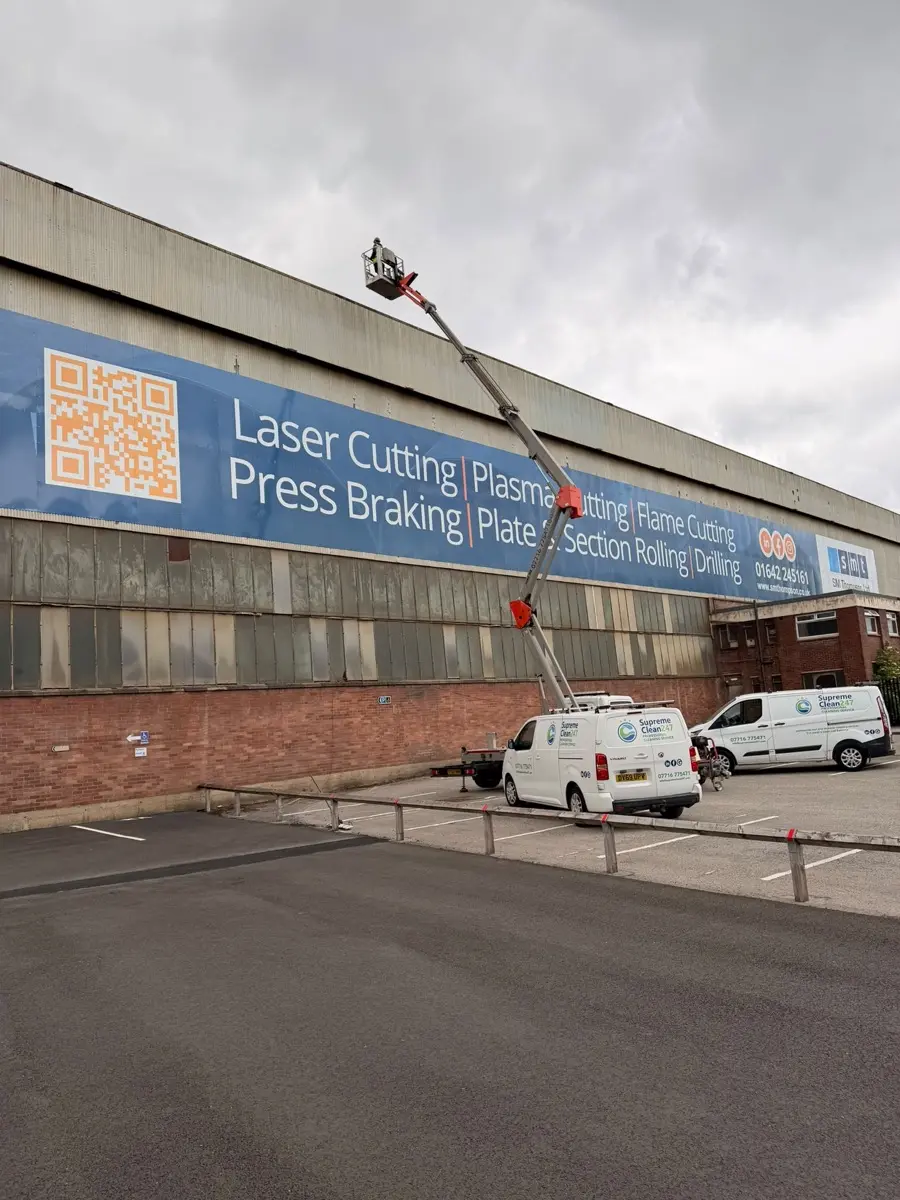 Operator working at height on an industrial unit signage banner