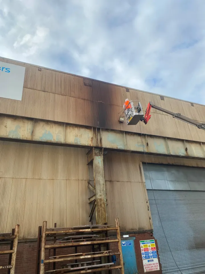 Supreme Clean operative pressure washing an industrial building
