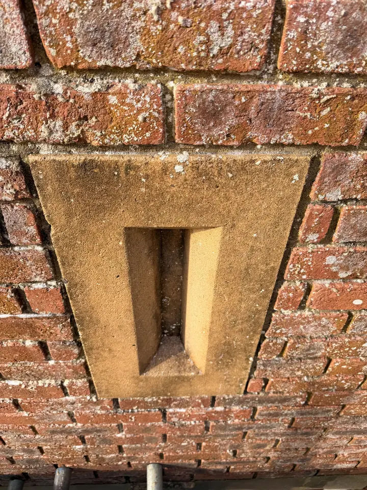 Lichen-stained stone keystone before DOFF steam cleaning