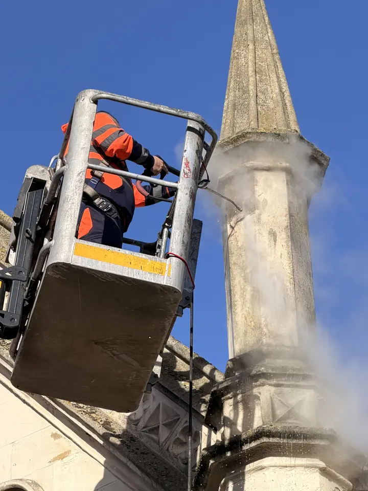 DOFF steam cleaning a stone spire at height