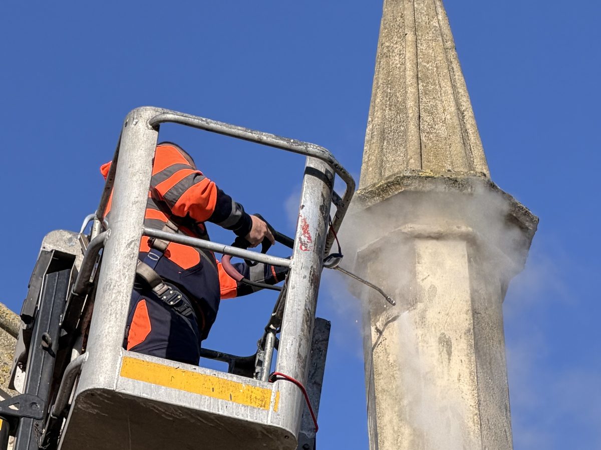 Supreme Clean operative DOFF steam cleaning a stone spire from the cherry picker basket
