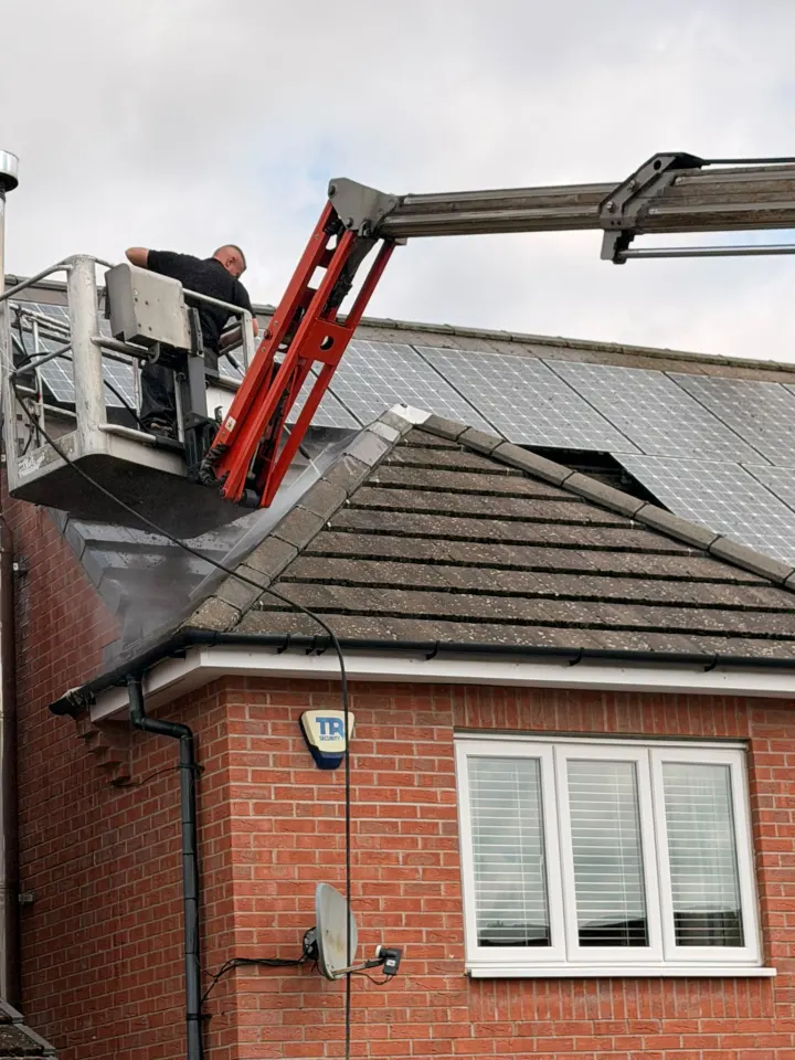 Operative cleaning a residential roof safely from a cherry picker
