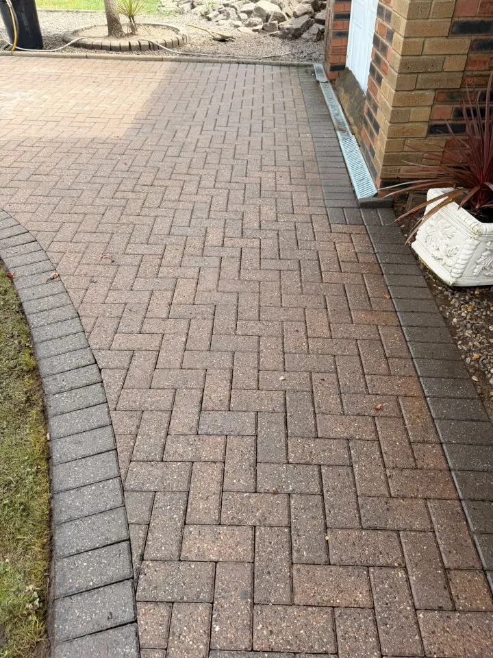 Cleaned block driveway beside landscaped planting