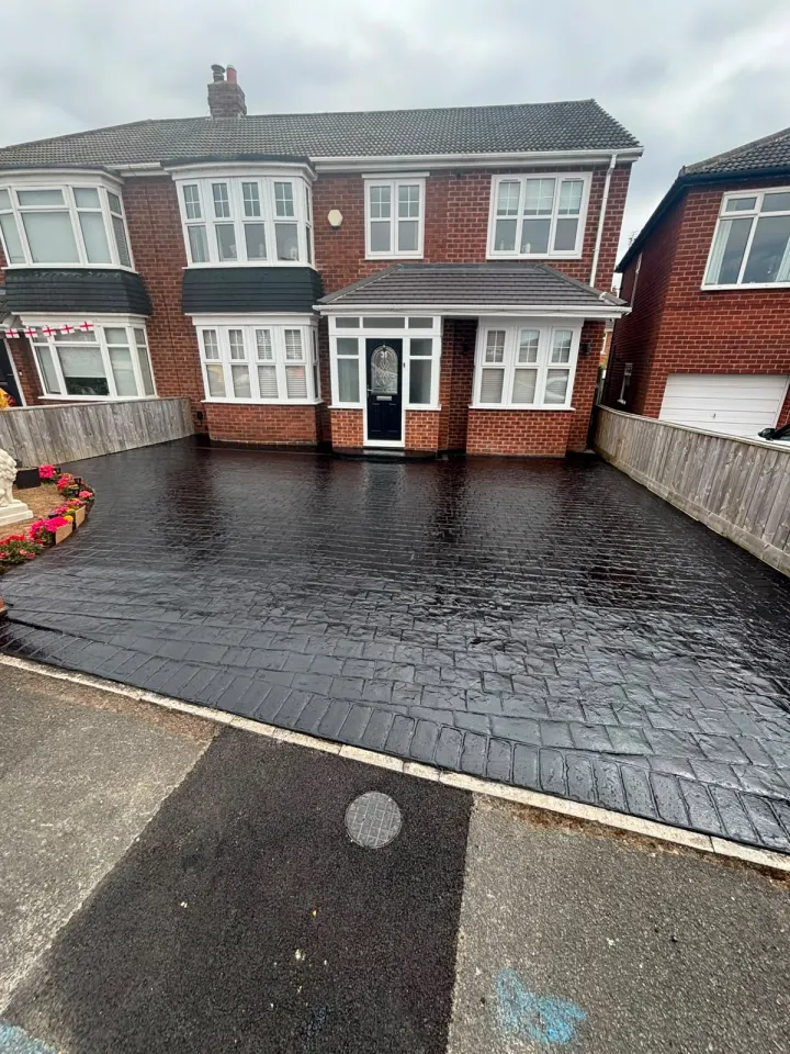 Wide black stamped concrete driveway after cleaning