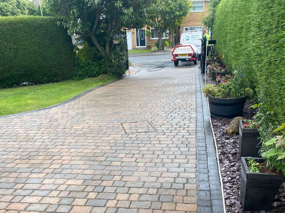 Landscaped block-paved driveway cleaned by Supreme Clean 247 with the branded van on site