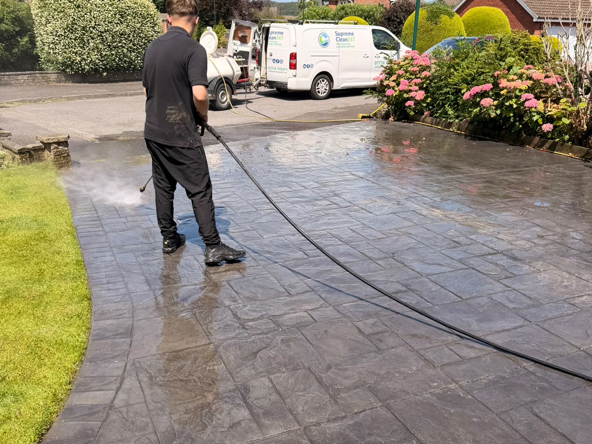 Supreme Clean 247 operative professionally pressure washing a residential patio